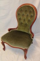 A Victorian beech spoon-back ladies' easy chair upholstered in green buttoned fabric on scroll legs