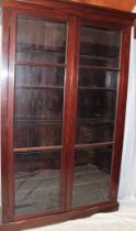 A Victorian mahogany bookcase with adjustable shelves enclosed by two full length glazed doors