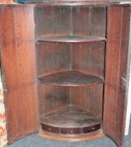 A George III oak and mahogany cross-banded hanging corner cabinet with small drawers and shelves
