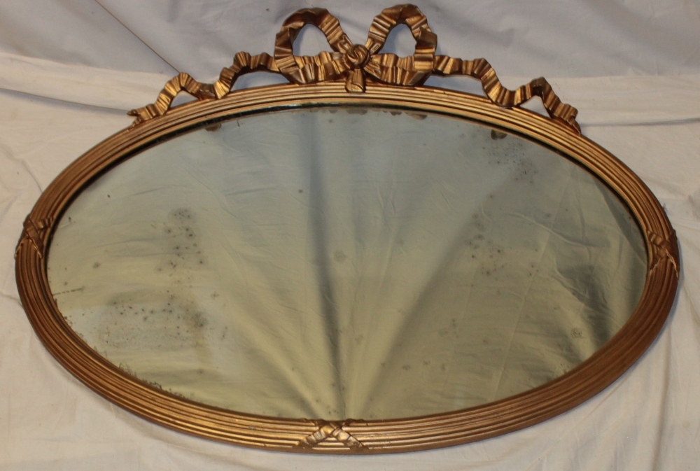 A 19th century oval wall mirror in gilt ribbon decorated frame,
