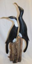 A Cornish carved wood sculpture of two cormorants on a wooden stump by Geoffrey Bickley of St.