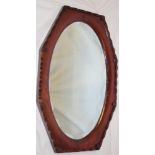 A bevelled oval wall mirror in polished mahogany angular frame,
