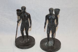 A pair of bronze figures of native males holding torches on circular bases 7½" high