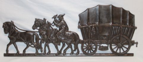 A bronzed iron wall plaque in the form of a wagon with horses,