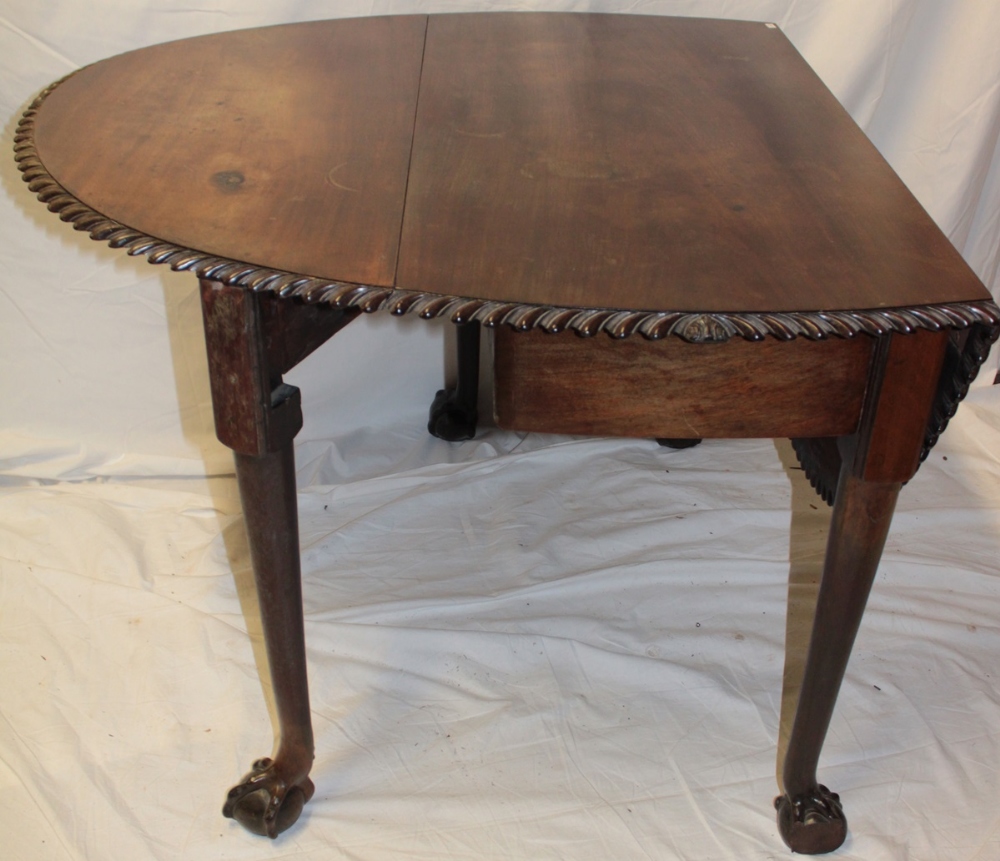 An Edwardian mahogany oval drop-leaf dining table with decorated edge on turned legs with claw and