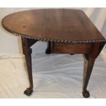 An Edwardian mahogany oval drop-leaf dining table with decorated edge on turned legs with claw and