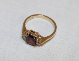 A 9ct gold Art Deco-style dress ring set a central garnet flanked by diamond chips (2.