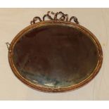 An old bevelled oval wall mirror in gilt frame with ribbon mount,