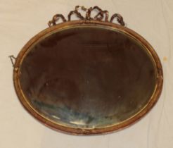 An old bevelled oval wall mirror in gilt frame with ribbon mount,