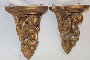 A pair of gilt plaster semi-circular wall plaques with cherub supports,