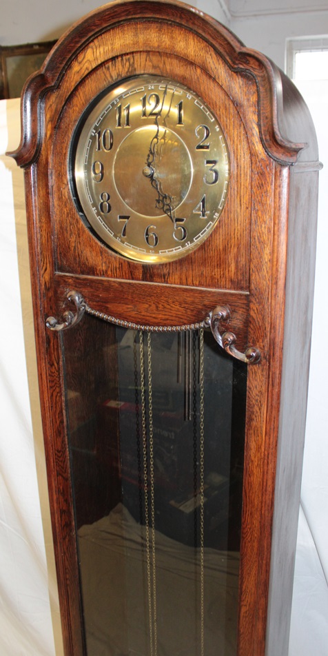 A 1920's/30's grandfather clock with brass circular dial in oak glazed arched traditional case