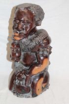An African carved hardwood figure of a kneeling male craftsman,