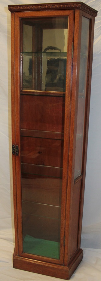 A polished oak slim collector's display case with glass shelves and part mirror back enclosed by a