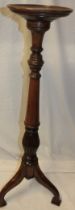 A reproduction mahogany circular torchere with fluted column and tripod base