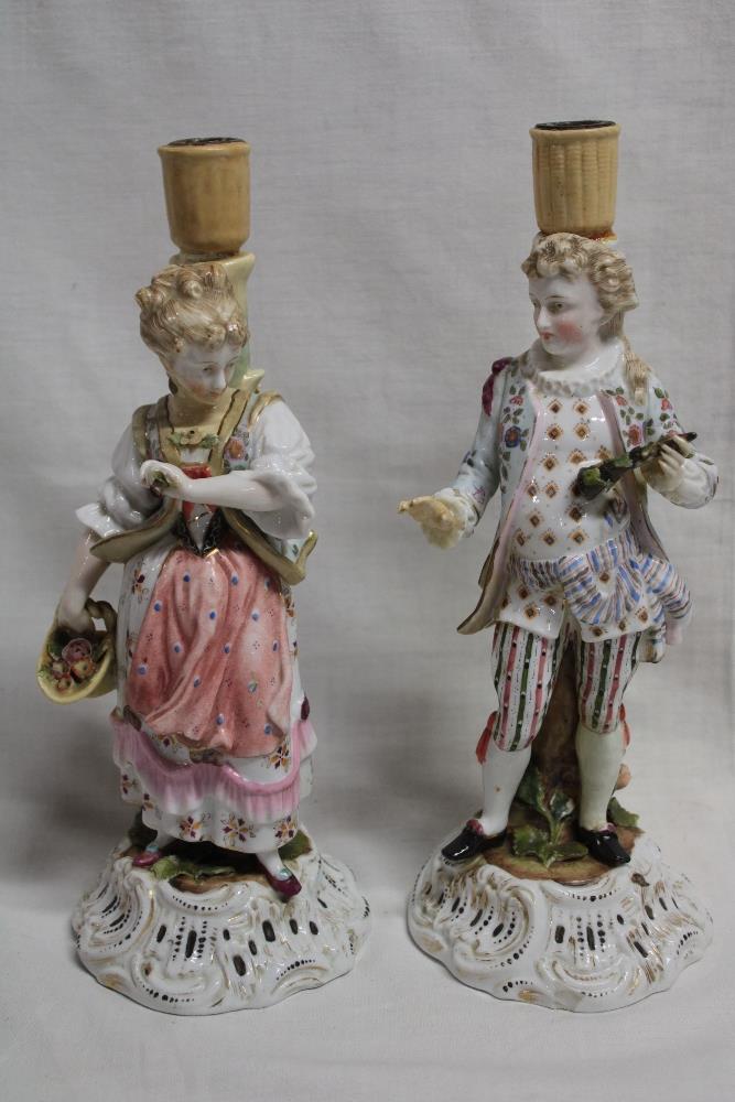 A pair of German porcelain ornamental candlesticks as a classical male and female on scroll-shaped