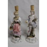 A pair of German porcelain ornamental candlesticks as a classical male and female on scroll-shaped