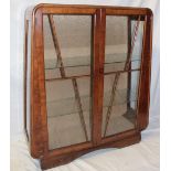 A 1930's walnut Art Deco angular display cabinet with glass shelves enclosed by two glazed doors,