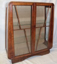 A 1930's walnut Art Deco angular display cabinet with glass shelves enclosed by two glazed doors,