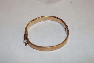 A 9ct gold oval bangle with engraved decoration (8.