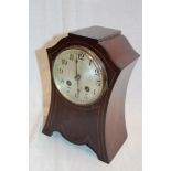 An Art Nouveau-style mantel clock with silvered circular dial in inlaid mahogany case