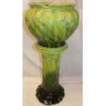 A green glazed pottery jardiniere with raised scroll decoration on matching green glazed stand,