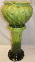 A green glazed pottery jardiniere with raised scroll decoration on matching green glazed stand,