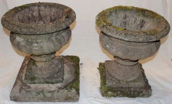 A pair of weathered garden classical-shaped urns on square bases 16" high