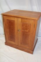 A polished oak cupboard with shelves enclosed by two panelled doors,