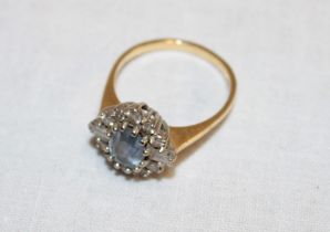 An 18ct gold dress ring set central aquamarine surrounded by diamonds (4.