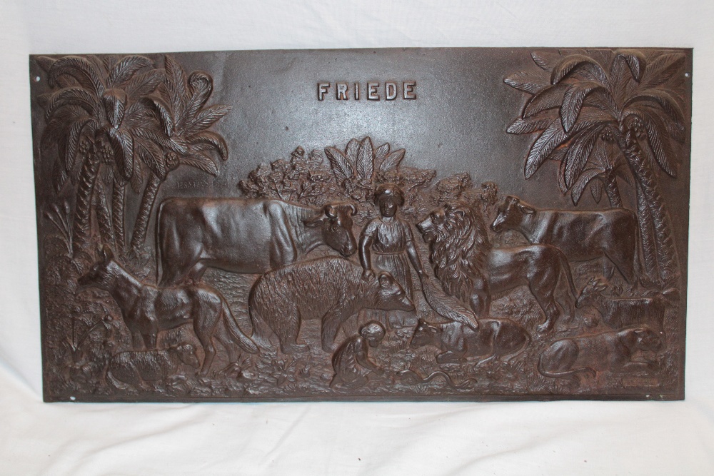 An old cast-iron rectangular plaque "Friede" depicting a young girl amongst animals and palm trees