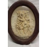 A 19th century carved plaster oval panel depicting a crucifixion scene in velvet lined frame with