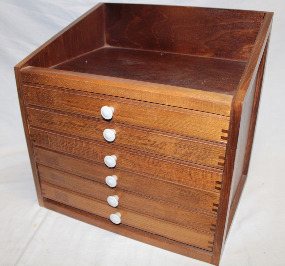 A stained wood table top collector's cabinet of six shallow fitted drawers,