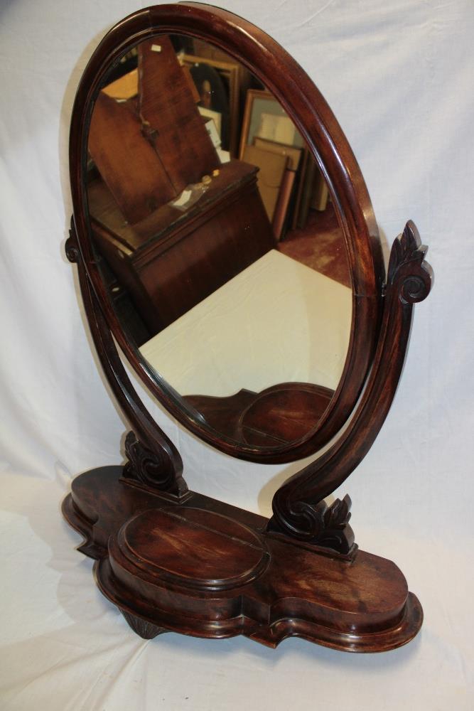 A Victorian mahogany oval swing toilet mirror on scroll-shaped supports,