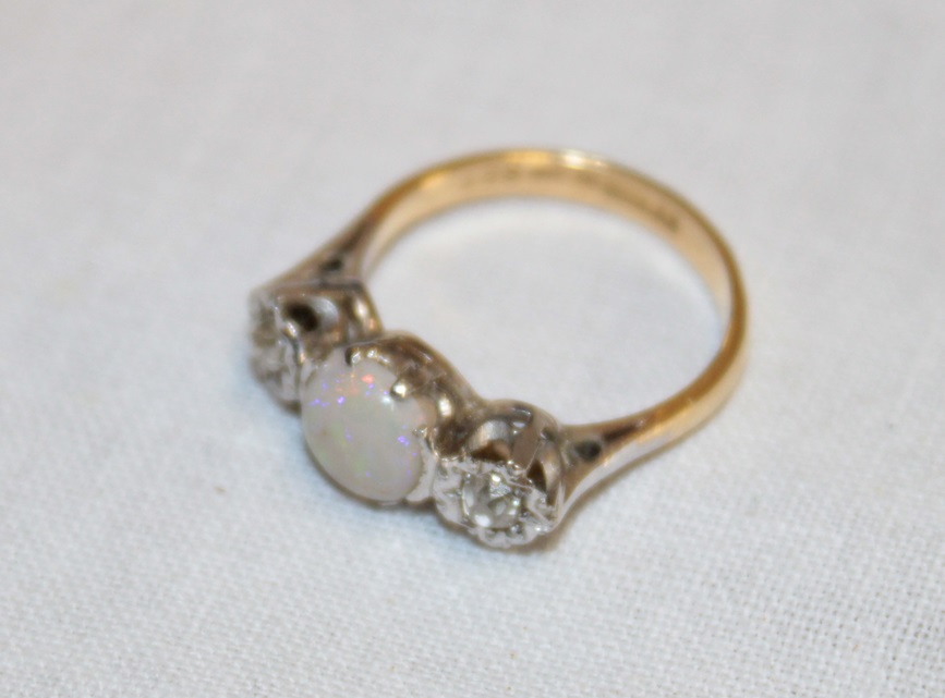 An 18ct gold engagement ring with platinum shoulders set a central opal flanked by two diamonds (2.