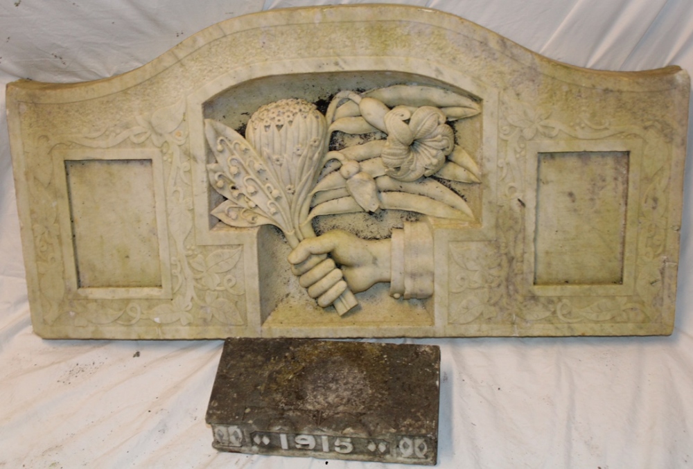 An old carved marble arched panel depicting a hand with flowers,