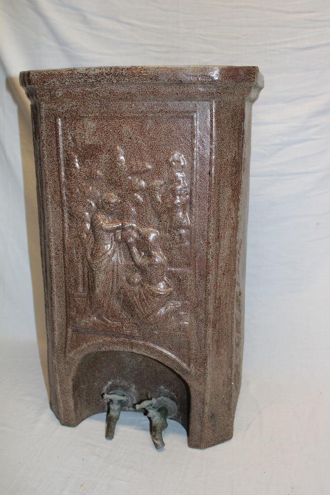 An old Continental pottery rectangular water filter with figure decoration and two base taps,