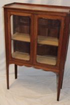 A polished mahogany display cabinet with shelves enclosed by two glazed doors on square tapered