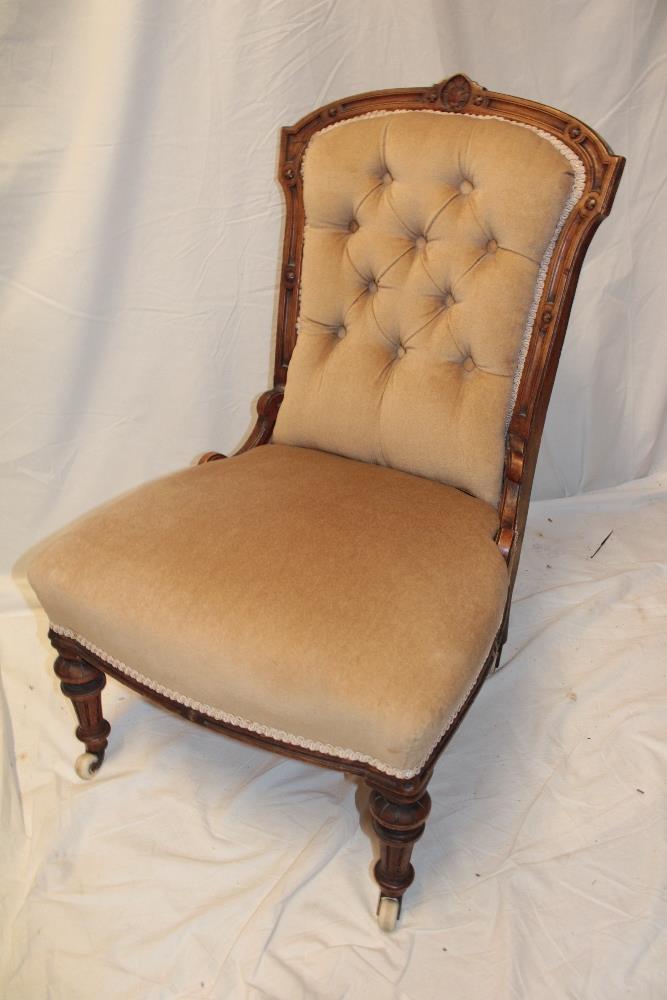 A Victorian carved walnut easy chair upholstered in buttoned fabric on turned tapered legs with