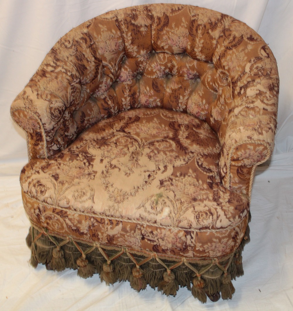 A Victorian tub-style easy chair upholstered in original floral fabric with tassled apron