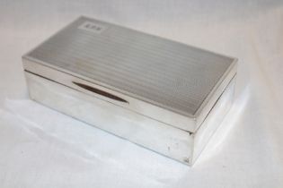 A George V silver rectangular cigarette box with engine turned decoration and engraved initials,