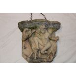 An unusual reconstituted stone garden wall bracket decorated in relief with a nude figure and goat