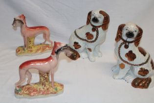 A pair of Victorian Staffordshire pottery figures of greyhounds with hare on oval bases (one af),