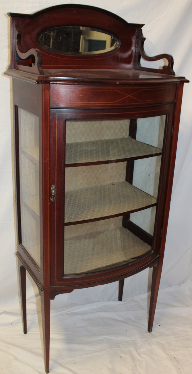 A late Victorian inlaid mahogany bow fronted display cabinet with fabric lined shelves enclosed by