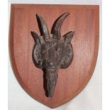 An old cast-iron plaque of a billy goat's head, mounted on a wooden shield,