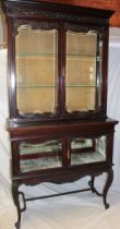 A late Victorian carved mahogany display cabinet with cupboard enclosed by two decorated glazed