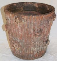 An old terracotta circular planter with rustic decoration in the form of a tree trunk,