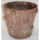 An old terracotta circular planter with rustic decoration in the form of a tree trunk,