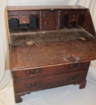 A 19th century oak bureau with numerous pigeon holes and drawers enclosed by a fall front above