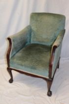 An Edwardian mahogany easy chair upholstered in green fabric on cabriole legs with claw and ball