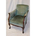 An Edwardian mahogany easy chair upholstered in green fabric on cabriole legs with claw and ball